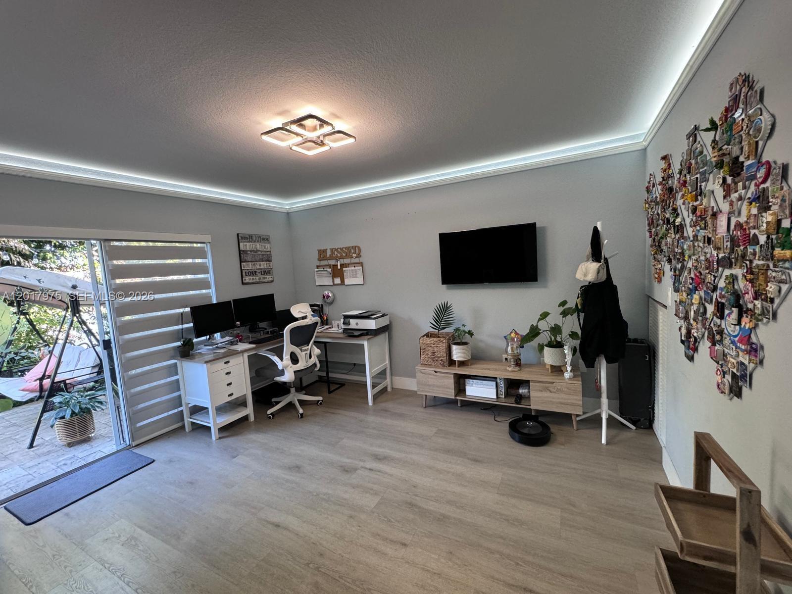 A home office features a desk, television, wall-mounted magnet collection, and sliding glass doors — 8851 NW 110th Pl # 1407, Doral FL 33178, DORAL, FL
