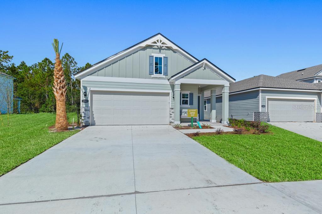 A single-story house with light green siding, a two-car garage, and a covered front porch — 1341 RIBBON PLACE, PALM COAST, FL