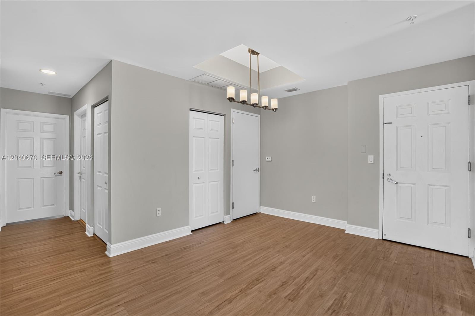This room features light gray walls, wood-look flooring, a chandelier, and several white doors — 3232 SW 22nd Ter # 601, Miami FL 33145, MIAMI, FL