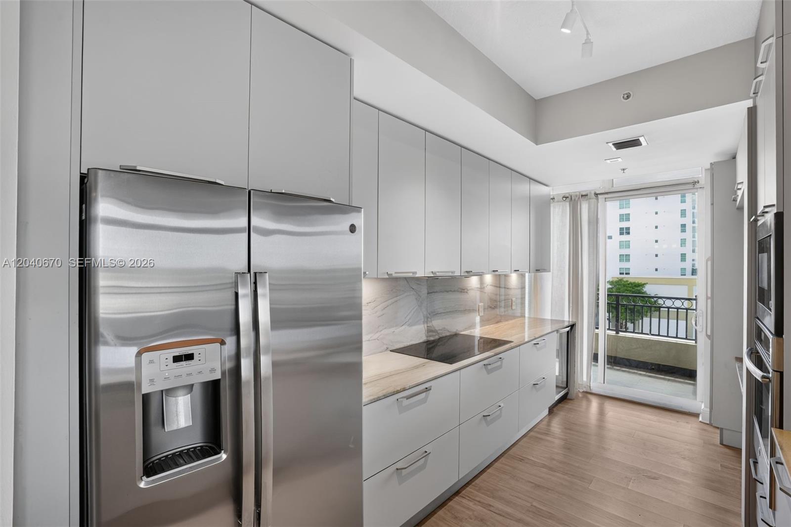 A modern kitchen features stainless steel appliances, light gray cabinetry, and a marble-patterned backsplash — 3232 SW 22nd Ter # 601, Miami FL 33145, MIAMI, FL