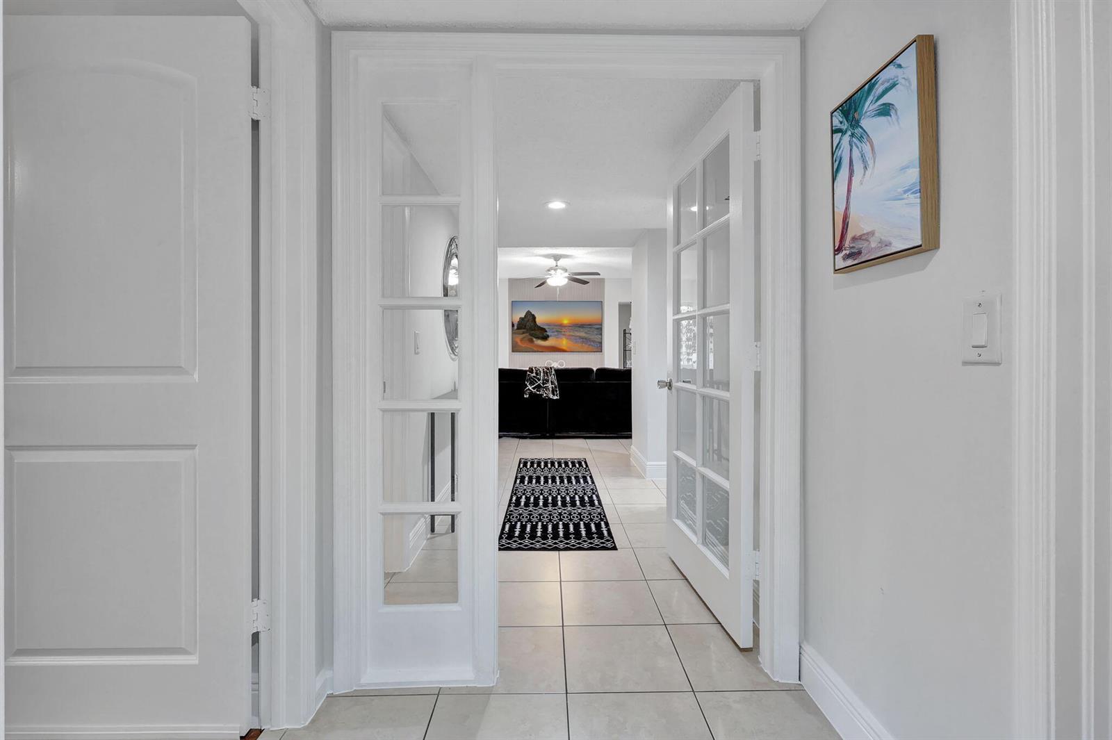 A hallway with tile floors leads through glass French doors into a living room — 12641 Westhampton Circle # C311, Wellington FL 33414, WELLINGTON, FL