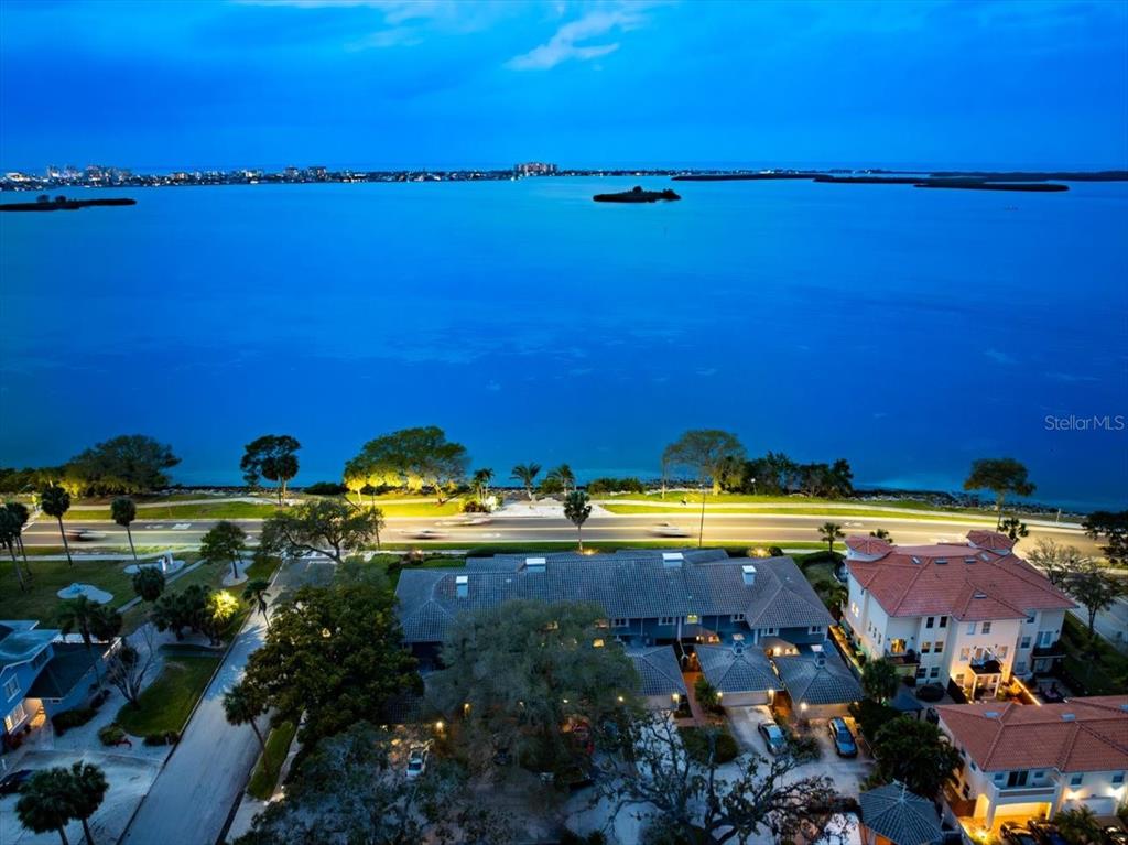 An aerial view shows a multi-story residential building near a road and a large bay — 2087 EDGEWATER DRIVE UNIT C, CLEARWATER, FL