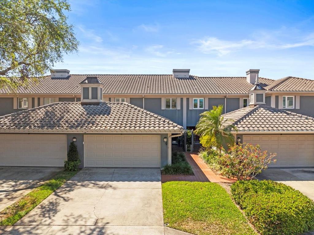 A multi-unit townhouse exterior features beige garage doors, gray siding, and a tiled roof — 2087 EDGEWATER DRIVE UNIT C, CLEARWATER, FL