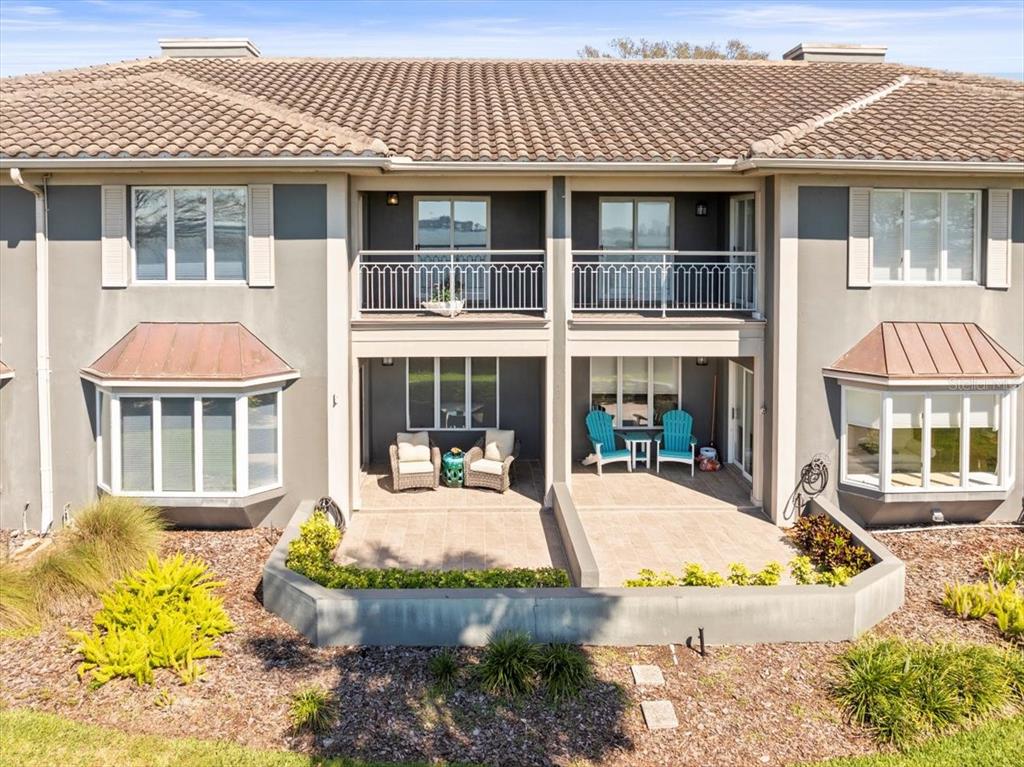 A two-story building exterior features two ground-level patios, upper balconies, and bay windows — 2087 EDGEWATER DRIVE UNIT C, CLEARWATER, FL