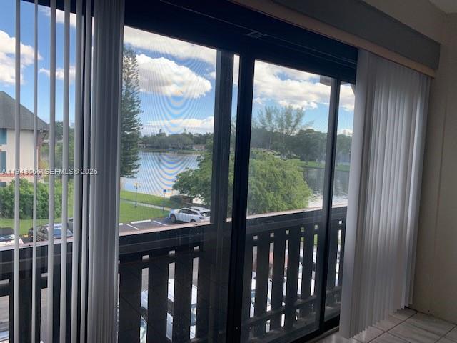 A view of a lake and parking lot seen through a sliding glass door — 3710 Inverrary Dr # 3K, Lauderhill FL 33319, LAUDERHILL, FL