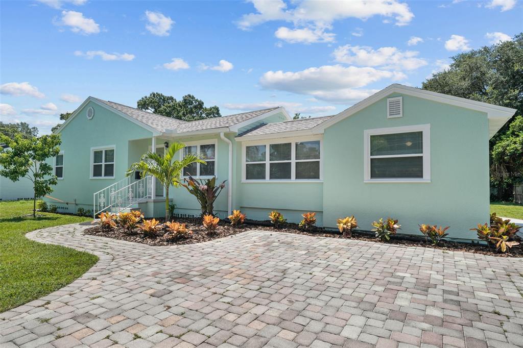 A light green single-story house features a paved driveway and a landscaped front garden — 814 W INDIANA AVENUE, TAMPA, FL