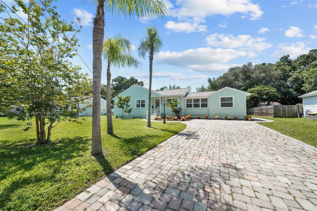 A light green single-story house with a paved driveway and palm trees in the front yard — 814 W INDIANA AVENUE, TAMPA, FL
