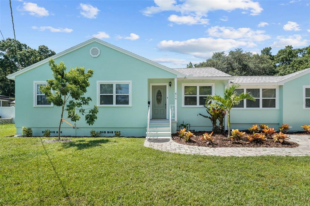 A light green single-story house with a front door, windows, and a landscaped yard — 814 W INDIANA AVENUE, TAMPA, FL