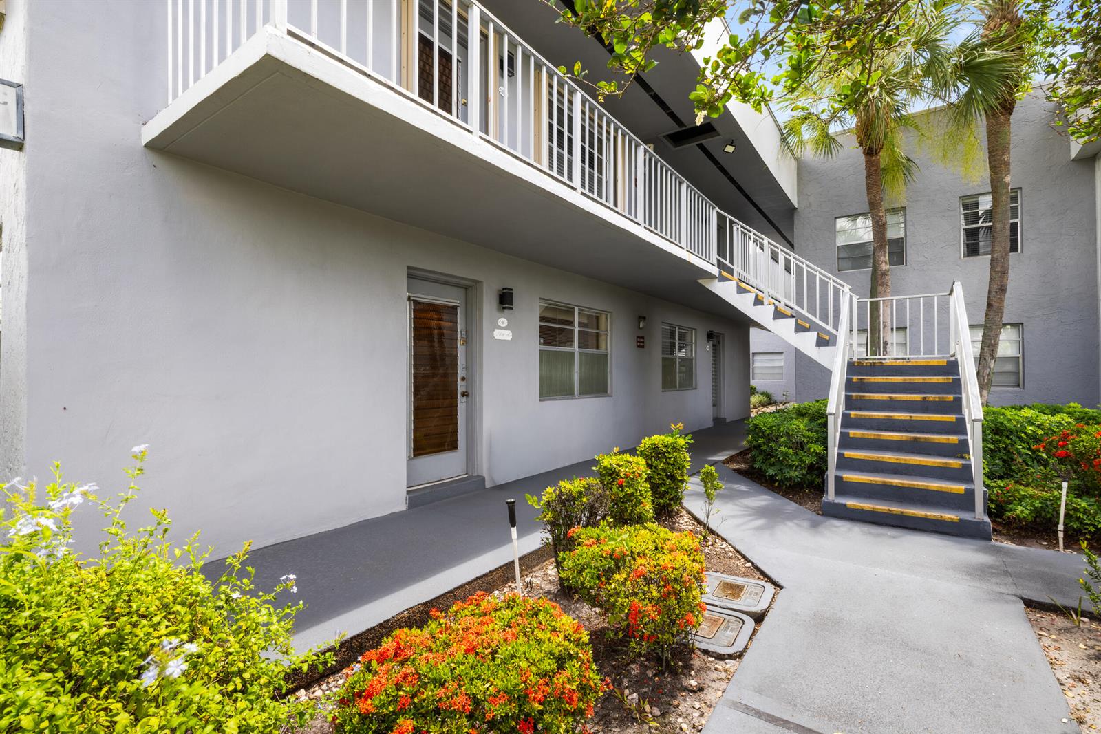 An exterior view of a two-story apartment building with a staircase and walkway — 97 Flanders # C, Delray Beach FL 33484, DELRAY BEACH, FL
