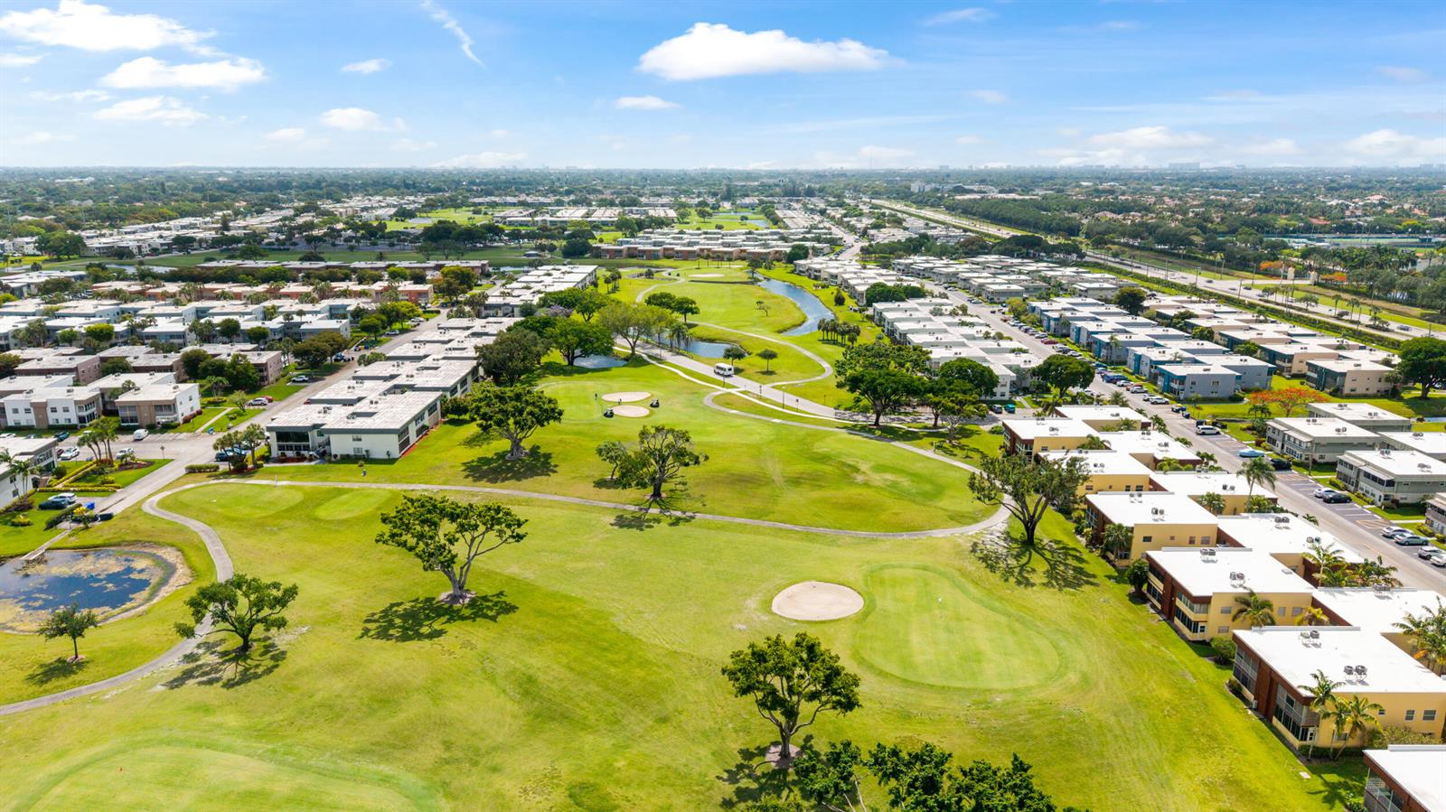 An aerial view shows a golf course surrounded by multi-story residential apartment buildings — 97 Flanders # C, Delray Beach FL 33484, DELRAY BEACH, FL