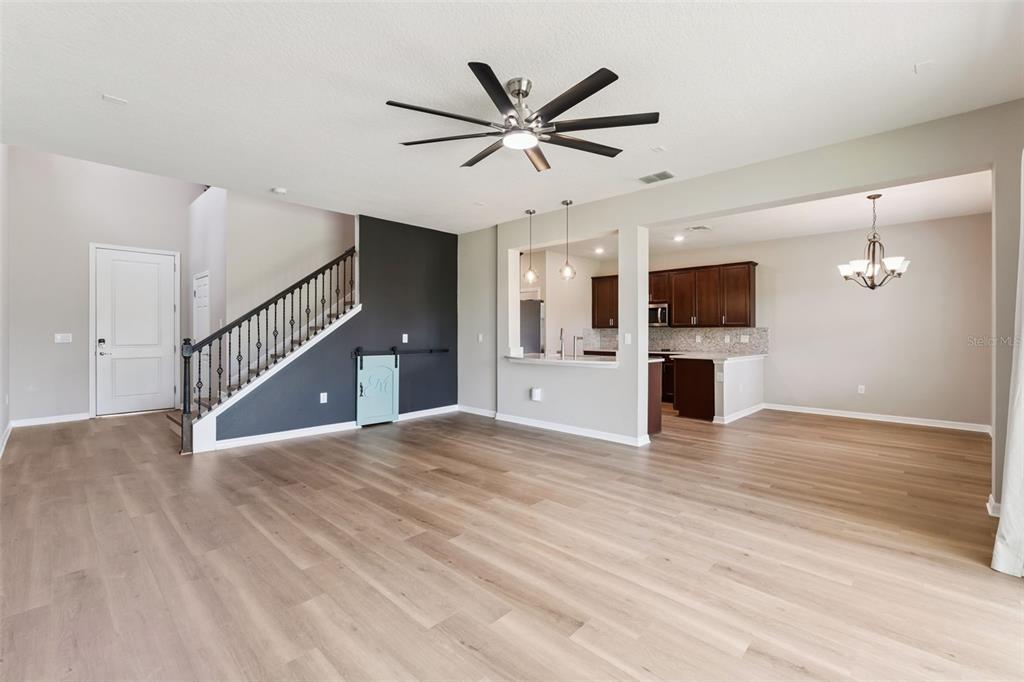 An open-concept living area features wood-look flooring, a staircase, and a kitchen with dark cabinetry — 2766 BOBCAT CHASE BOULEVARD, WINTER GARDEN, FL
