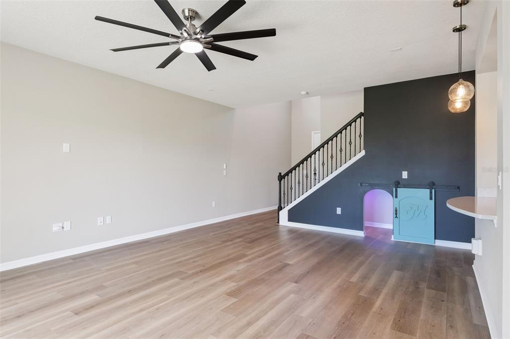 A living room with wood-look flooring, a ceiling fan, and a staircase with a playhouse — 2766 BOBCAT CHASE BOULEVARD, WINTER GARDEN, FL