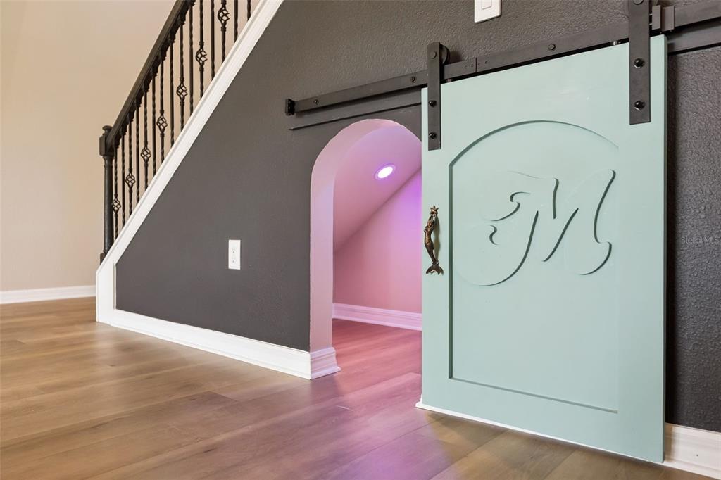 A small arched play space under a staircase features a light green sliding barn door — 2766 BOBCAT CHASE BOULEVARD, WINTER GARDEN, FL