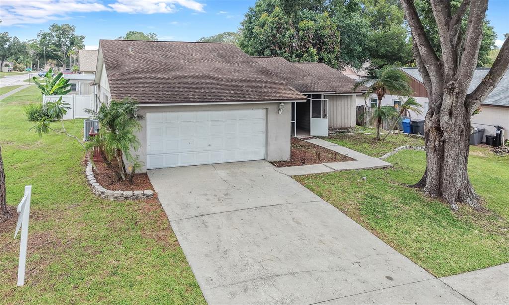 An exterior view of a single-story house with a concrete driveway and a two-car garage — 1702 SOUTHWIND DRIVE, BRANDON, FL