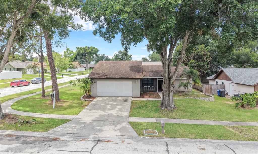 A single-story house with a two-car garage and large trees in the front yard — 1702 SOUTHWIND DRIVE, BRANDON, FL