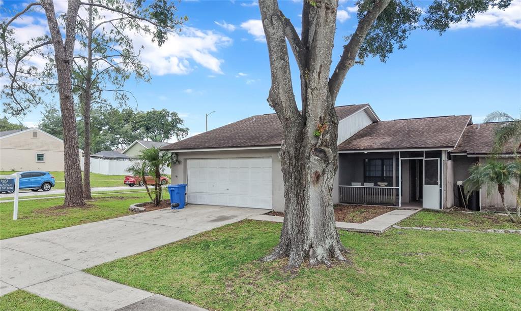A single-story house with a white garage door, a screened porch, and a large tree — 1702 SOUTHWIND DRIVE, BRANDON, FL