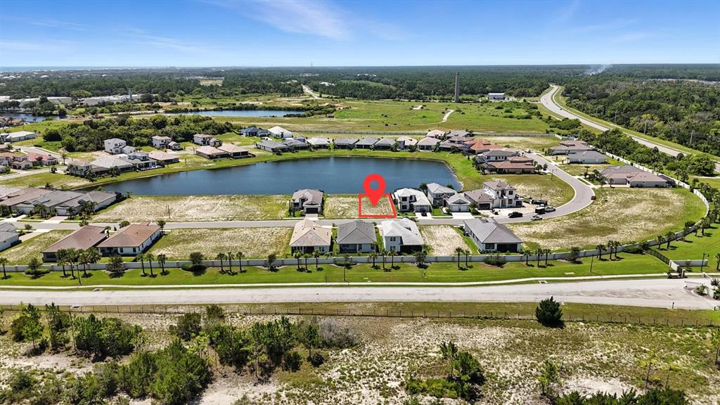 This aerial view shows a vacant residential lot marked with a red pin near a lake — 27 DEL PALMA DRIVE, PALM COAST, FL
