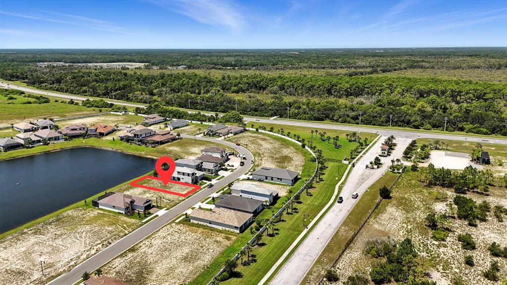 An aerial view shows a vacant residential lot highlighted in red next to a lake — 27 DEL PALMA DRIVE, PALM COAST, FL