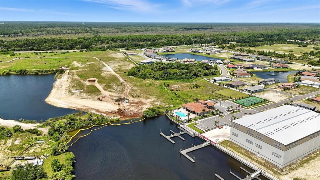 An aerial view shows a large warehouse, a community pool, boat docks, and surrounding lakes — 27 DEL PALMA DRIVE, PALM COAST, FL
