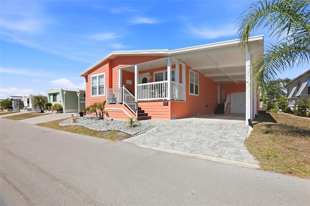 A peach-colored manufactured home features a front porch, a carport, and a paved driveway — 24717 SNOOK AVENUE UNIT 11D, PUNTA GORDA, FL
