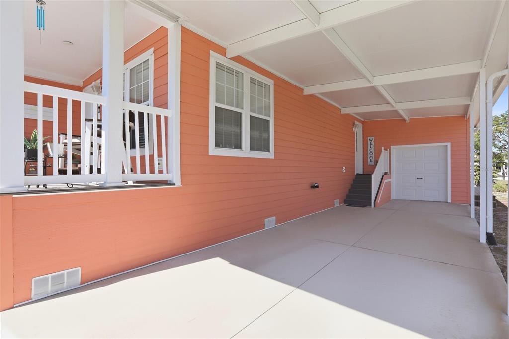 A peach-colored house exterior features a covered carport, a white porch railing, and stairs — 24717 SNOOK AVENUE UNIT 11D, PUNTA GORDA, FL