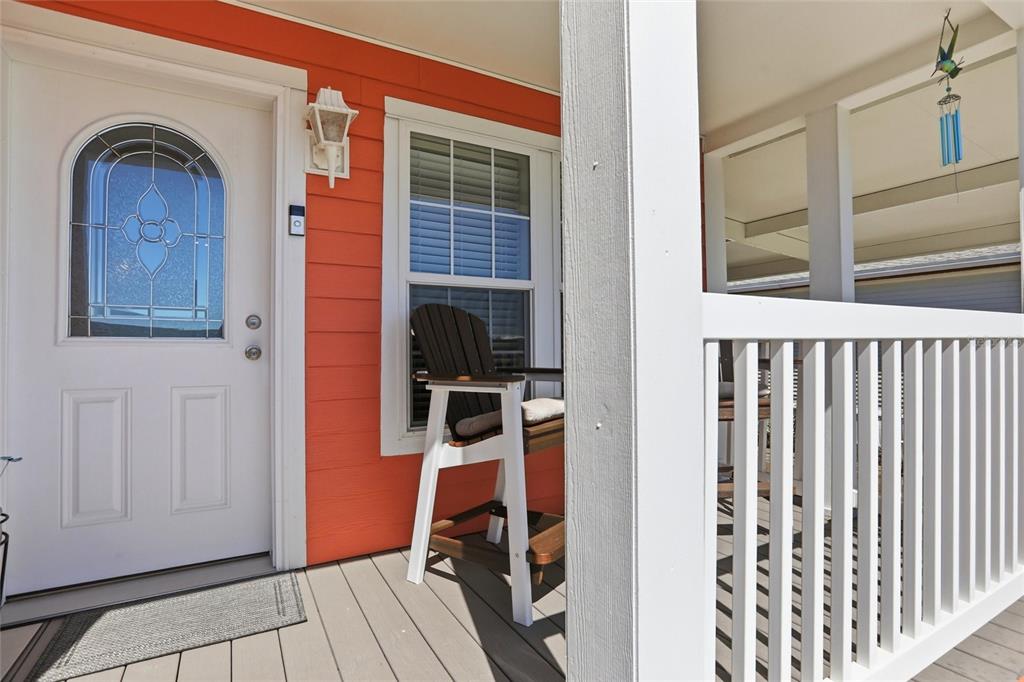 A white front door with a decorative window sits on a porch with orange siding — 24717 SNOOK AVENUE UNIT 11D, PUNTA GORDA, FL