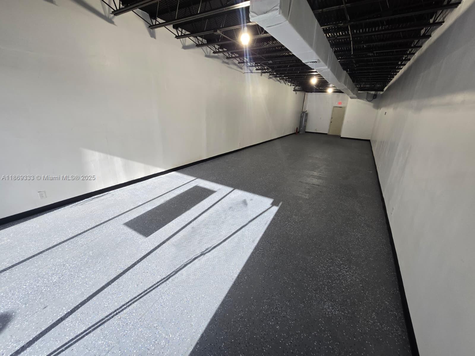 An empty commercial space features white walls, a black exposed ceiling, and speckled epoxy flooring — 2501 N State Road 7 # 2531, Margate FL 33063, MARGATE, FL