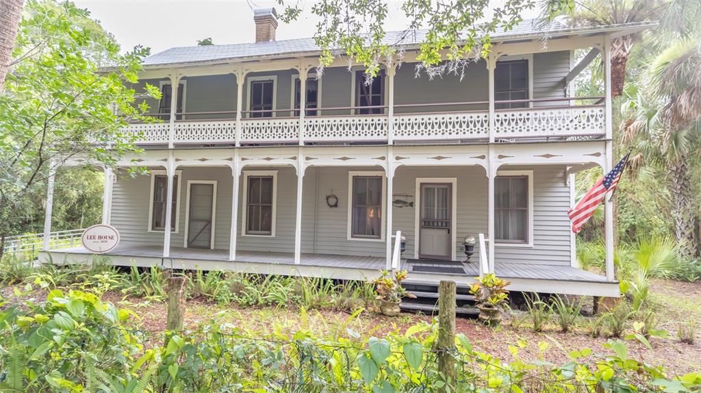 A two-story gray house with a wrap-around porch and decorative white railings — 200 PARK STREET, MELROSE, FL