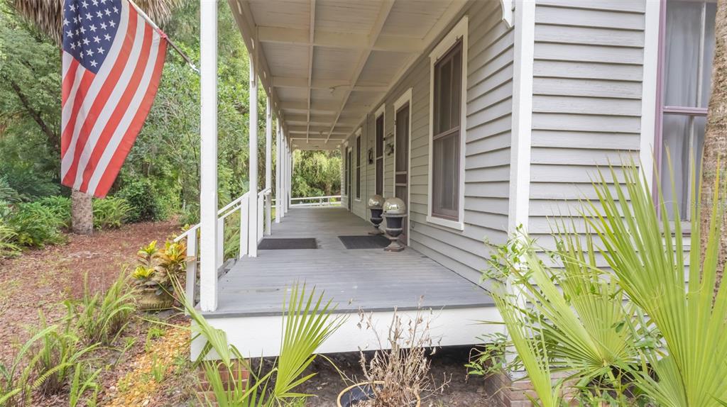 A wooden porch with a gray floor runs along the side of a gray house — 200 PARK STREET, MELROSE, FL
