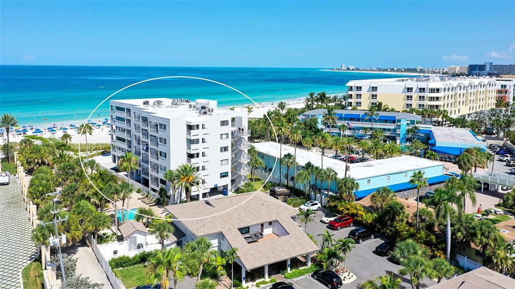 An aerial view shows a multi-story white apartment building near a sandy beach — 1001 POINT OF ROCKS ROAD UNIT 208, SARASOTA, FL