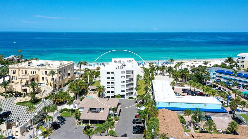 An aerial view shows a white multi-story apartment building situated near a sandy beach — 1001 POINT OF ROCKS ROAD UNIT 208, SARASOTA, FL
