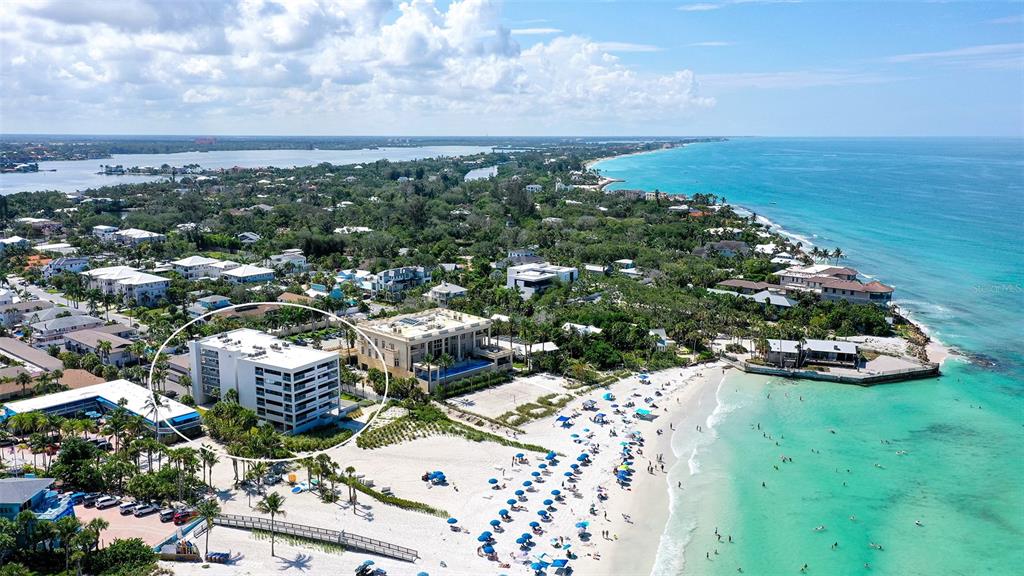 An aerial view shows a multi-story white apartment building near a sandy beach — 1001 POINT OF ROCKS ROAD UNIT 208, SARASOTA, FL