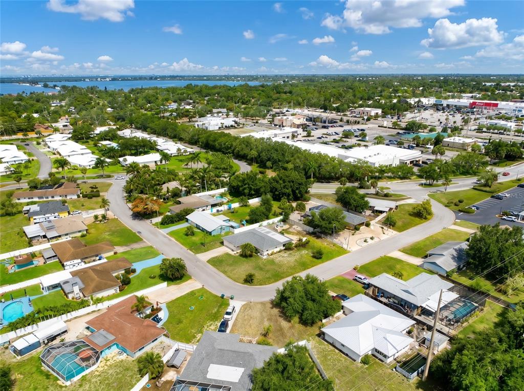 An aerial view shows a residential neighborhood with houses, swimming pools, and nearby commercial buildings — 7210 8TH AVENUE LOOP W, BRADENTON, FL