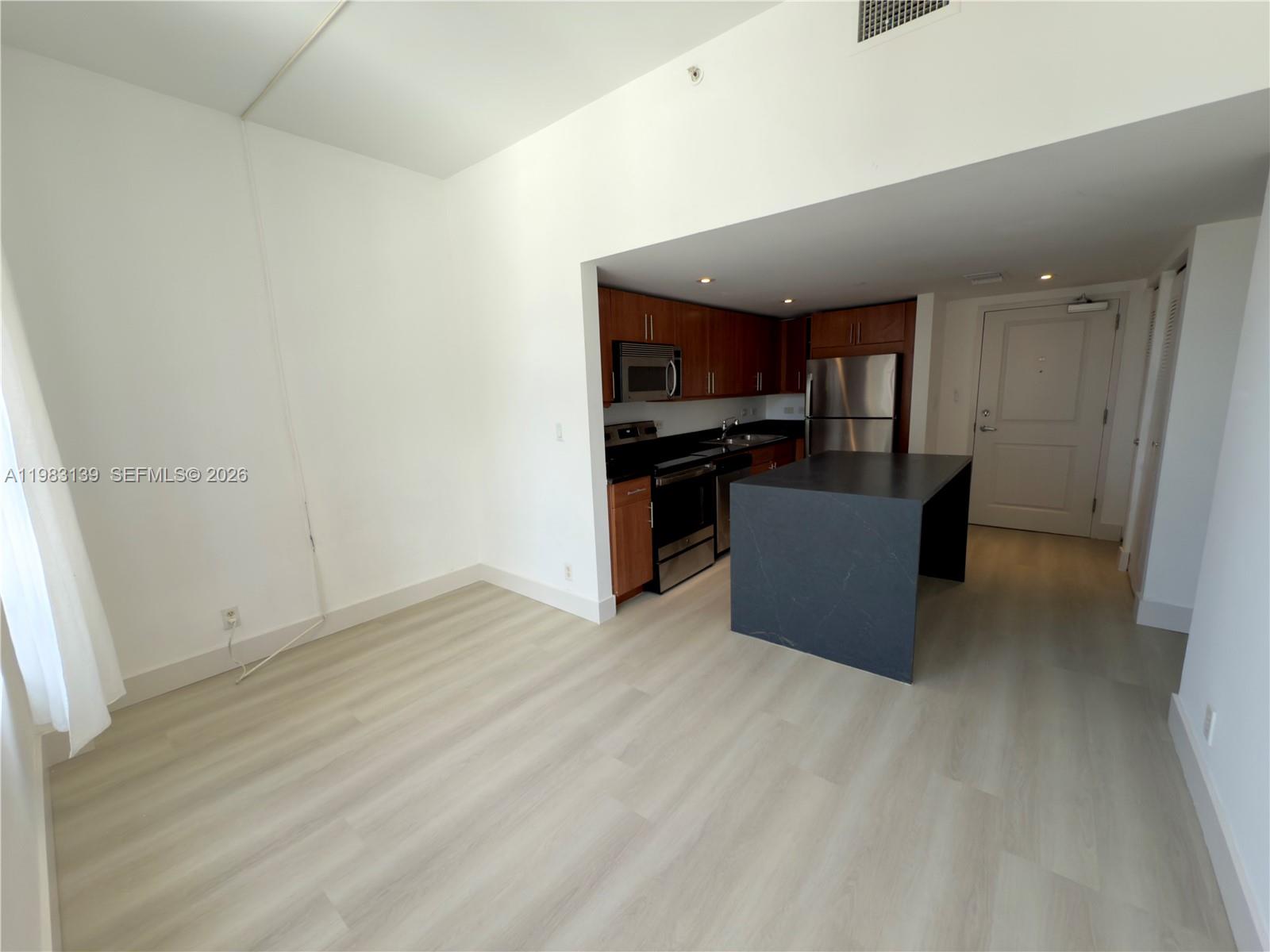 An open-concept kitchen with dark cabinets and a central island sits beside a living area — 111 E Flagler St # 805, Miami FL 33131, MIAMI, FL