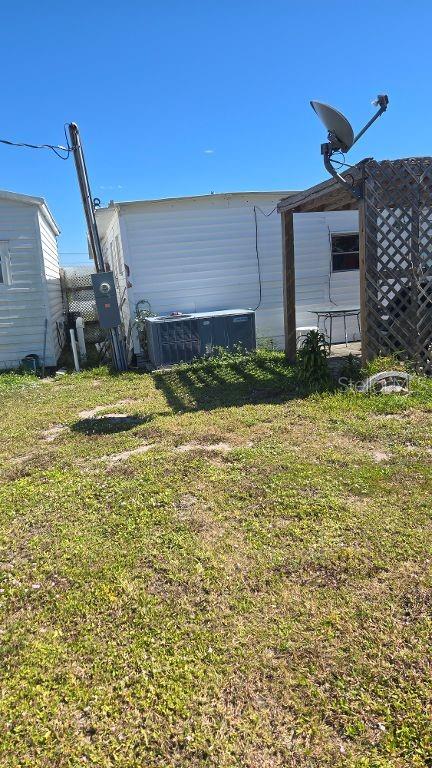 The exterior of a mobile home features a satellite dish, an HVAC unit, and siding — 1398 IBIS DRIVE, ENGLEWOOD, FL