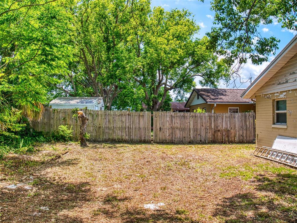 A backyard features a wooden fence, a small shed, and a tan house exterior — 310 LEGION PLACE, PORT ORANGE, FL