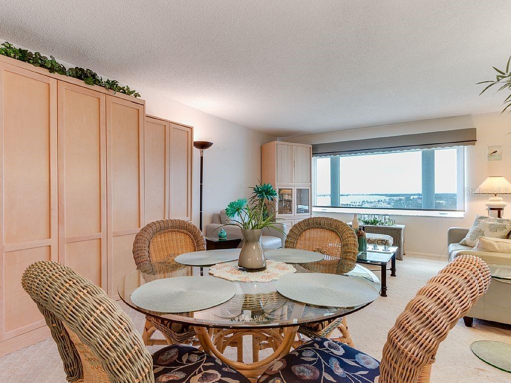 A dining area features a glass-topped table with wicker chairs and built-in light wood cabinetry — 4725 COVE CIRCLE UNIT 906, ST PETERSBURG, FL