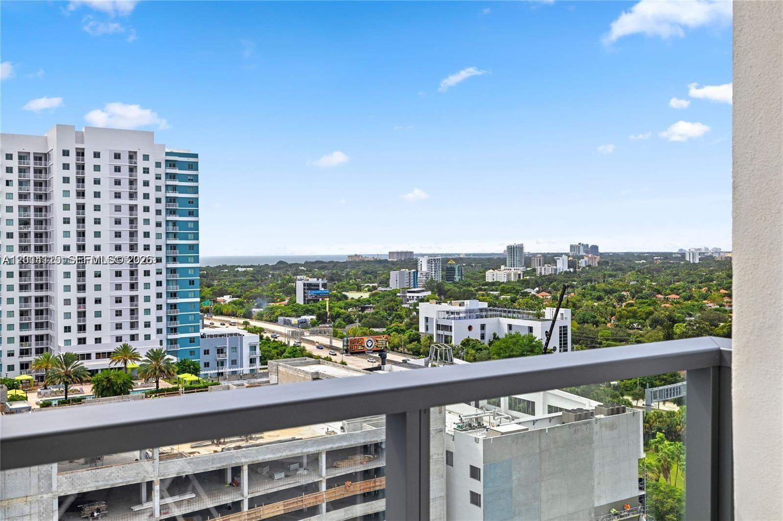 A high-angle view from a balcony overlooks a city skyline, highway, and surrounding greenery — 239 SW 9th St # 1502, Miami FL 33130, MIAMI, FL