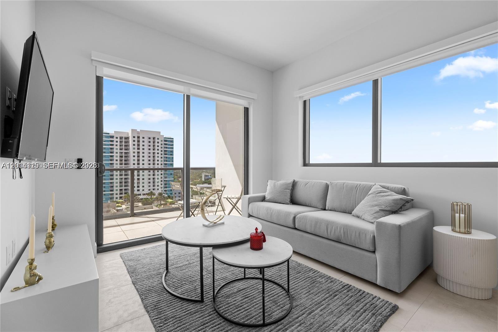 A modern living room features a gray sofa, nesting coffee tables, and a balcony view — 239 SW 9th St # 1502, Miami FL 33130, MIAMI, FL