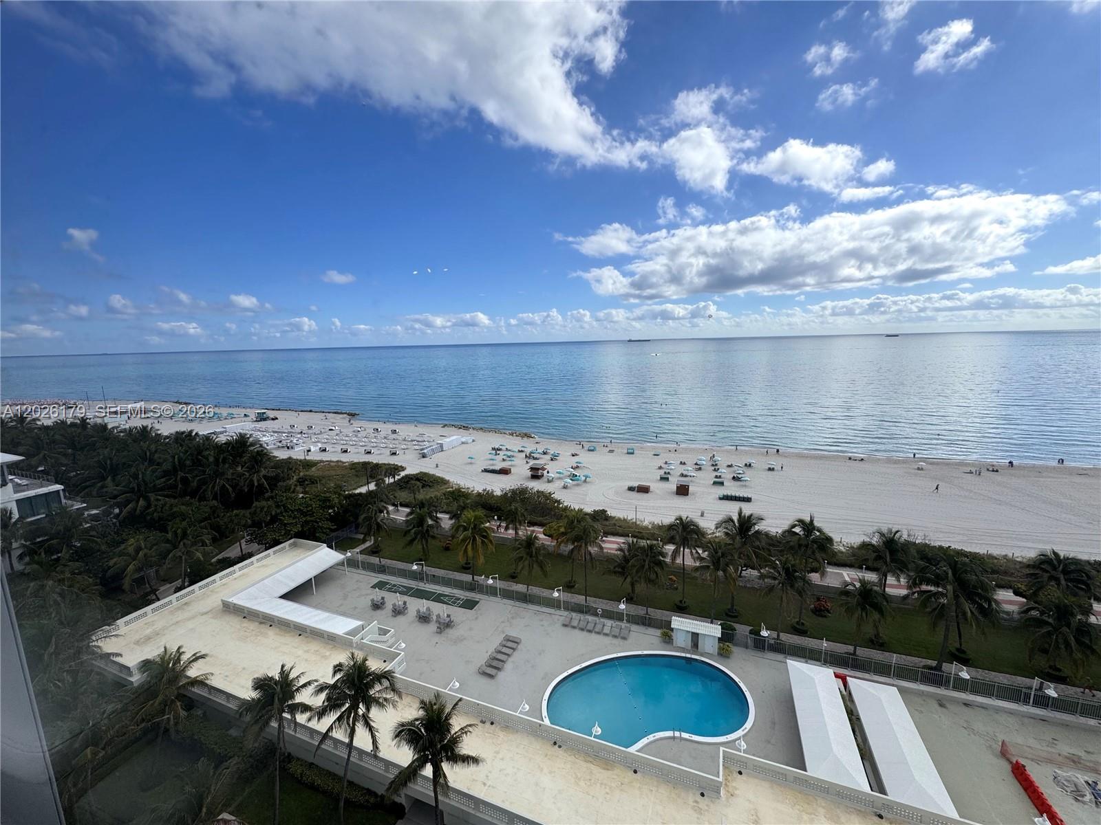An elevated view shows a swimming pool, palm trees, and a sandy beach by the ocean — 2899 Collins Ave # 1433, Miami Beach FL 33140, MIAMI BEACH, FL