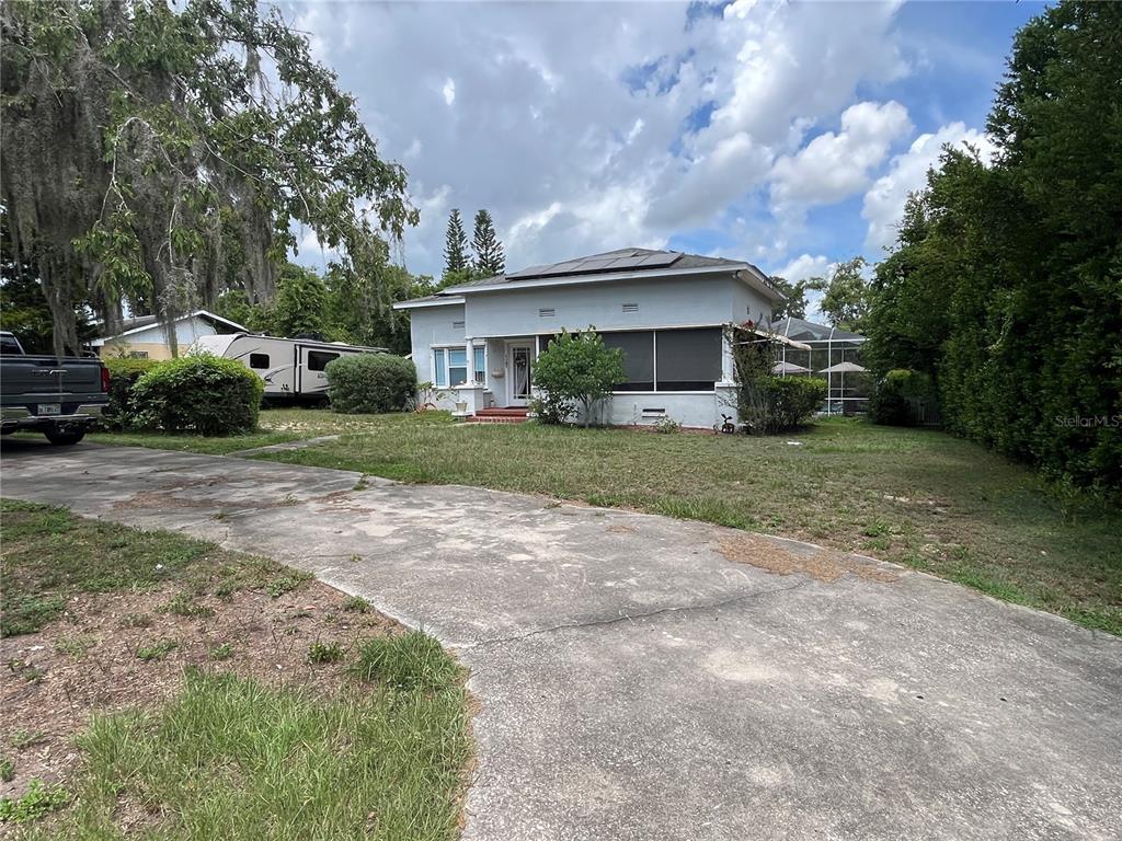 A single-story house with a concrete driveway, a screened porch, and solar panels on the roof — 1127 S LAKESHORE BOULEVARD, LAKE WALES, FL