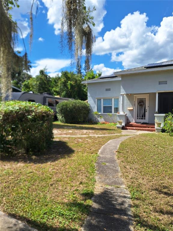 A concrete walkway leads to the front entrance of a light-colored house with solar panels — 1127 S LAKESHORE BOULEVARD, LAKE WALES, FL