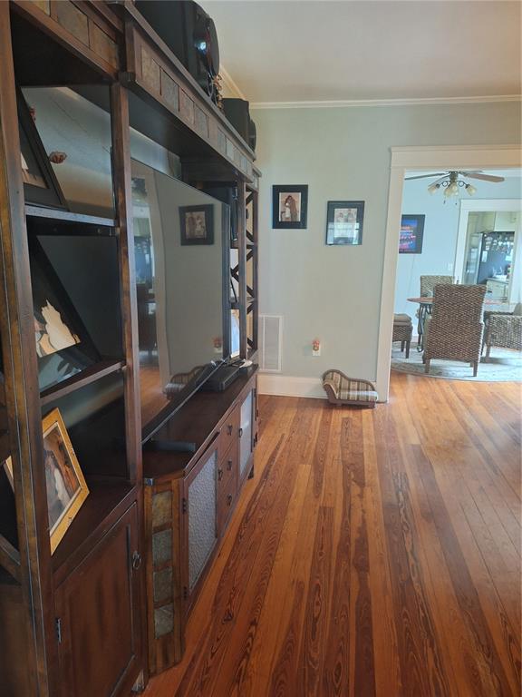 A living room features a large wooden entertainment center, hardwood floors, and a doorway view — 1127 S LAKESHORE BOULEVARD, LAKE WALES, FL
