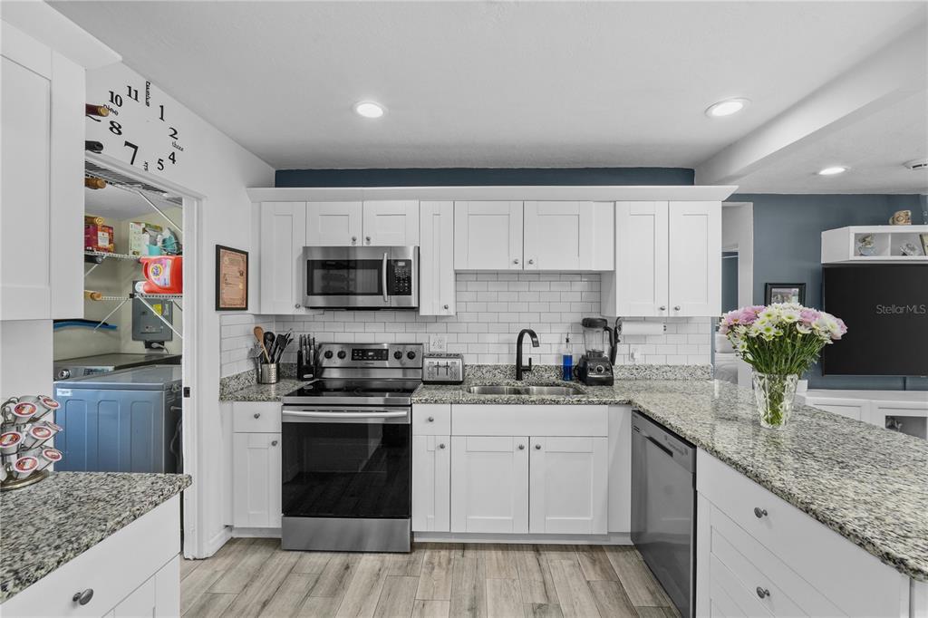 A kitchen features white cabinets, granite countertops, stainless steel appliances, and a subway tile backsplash — 3260 36TH AVENUE N, ST PETERSBURG, FL