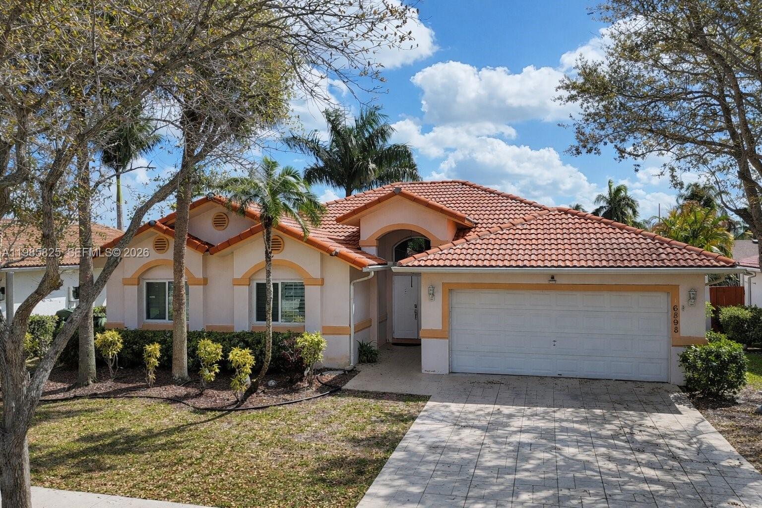 A single-story house with a tiled roof, a two-car garage, and a paved driveway — 16898 Crestview Ln, Weston FL 33326, WESTON, FL