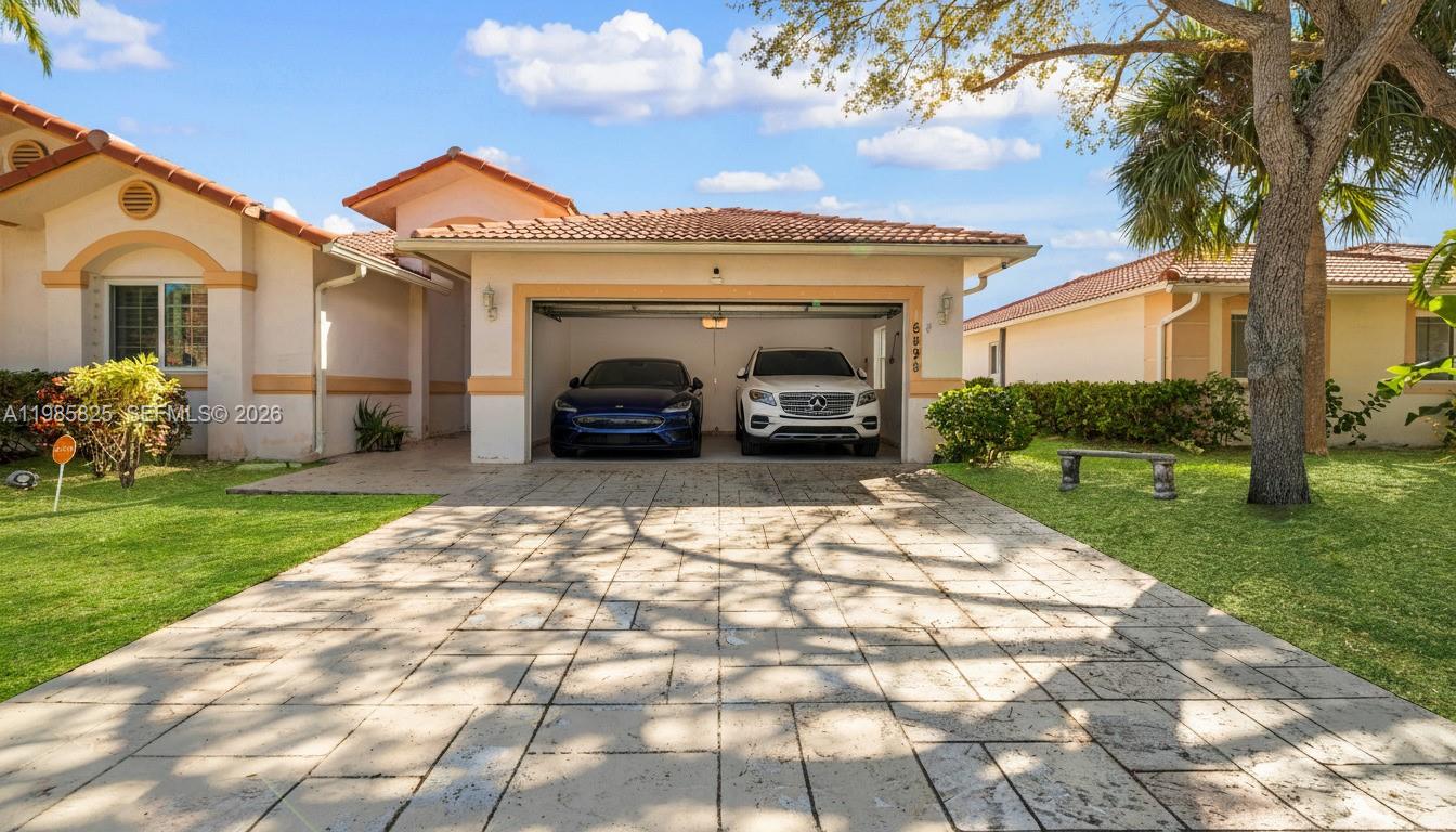 A single-story house with a two-car garage, tiled roof, and a paved driveway — 16898 Crestview Ln, Weston FL 33326, WESTON, FL