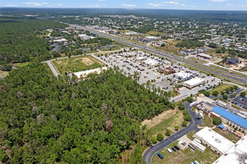 An aerial view shows a commercial shopping center adjacent to a large wooded area — 00 SAGHEER STREET, BROOKSVILLE, FL