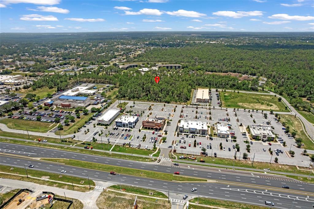 An aerial view shows a commercial shopping center with a red pin marking a wooded lot — 00 SAGHEER STREET, BROOKSVILLE, FL
