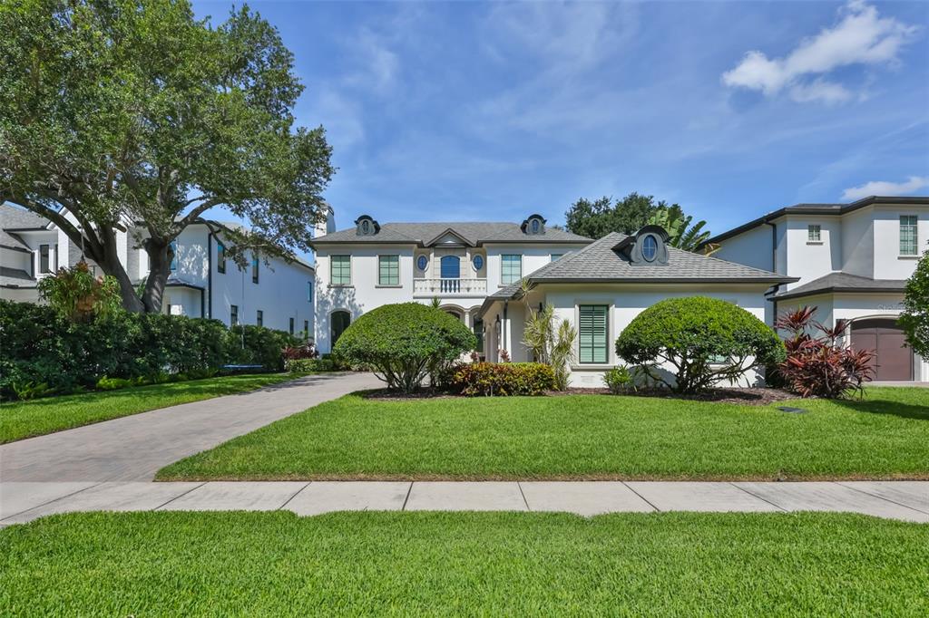 A two-story white house with a paved driveway, manicured lawn, and two rounded shrubs — 629 RIVIERA DRIVE, TAMPA, FL