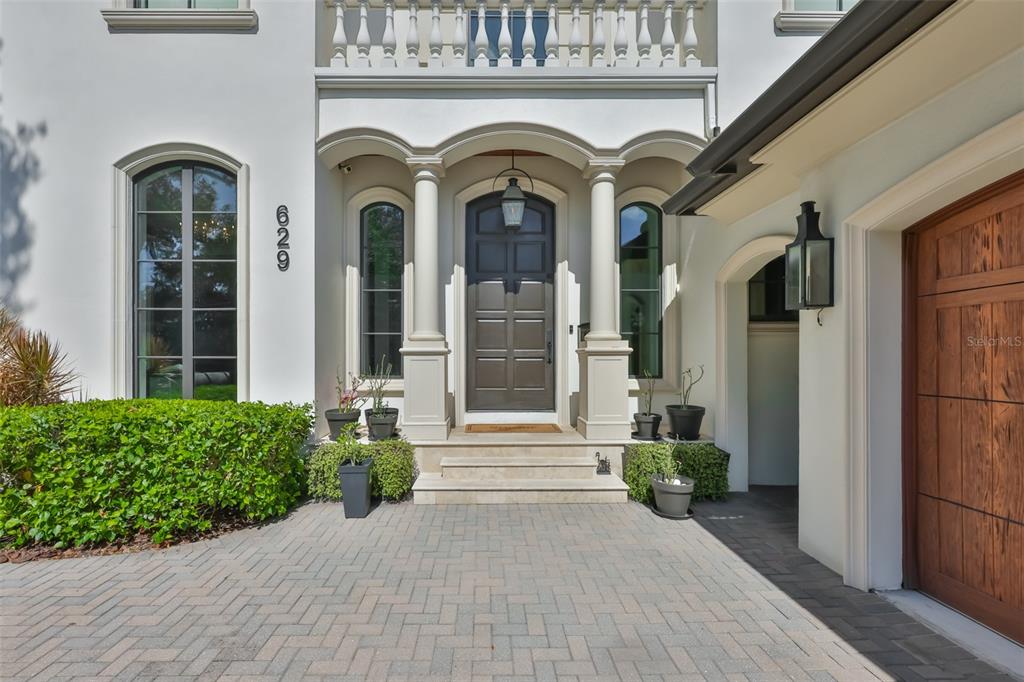 The exterior of a house features a dark front door, stone steps, and arched windows — 629 RIVIERA DRIVE, TAMPA, FL
